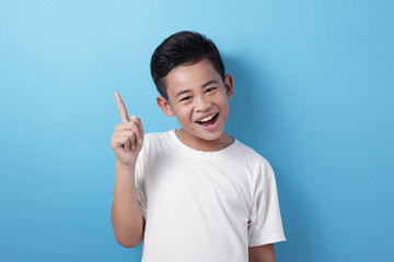 Happy Asian boy pointing finger up, having idea gesture