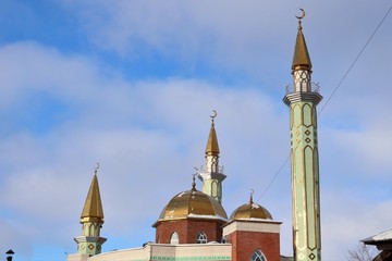 Domes and minarets of a mosque, blue sky with clouds.