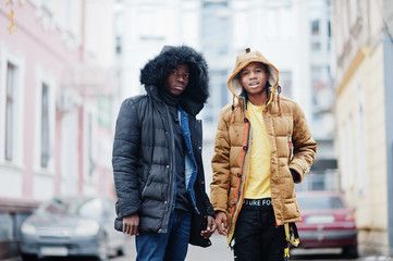 Two african male friends walking together, wear on jackets with hoodie.