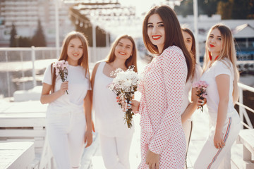 Beautiful girls with bouquet of flowers. Friends have fun in a summer park