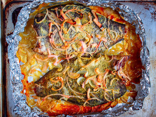 Tasty baked fish in foil on table close-up. Top view.