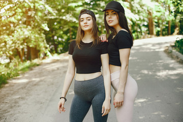 Beautiful sportsgirls in a summer forest. Ladies in a black top