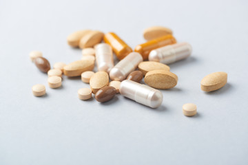 Multicolor vitamins and supplements on bright paper background. Concept for a healthy dietary supplementation. Close up. 