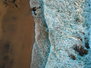 aerial view from a big wave crashing in a beach. Drone view