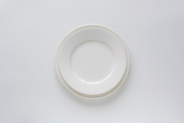 Empty white plate on white background top view. Minimalism style composition. Table settings.