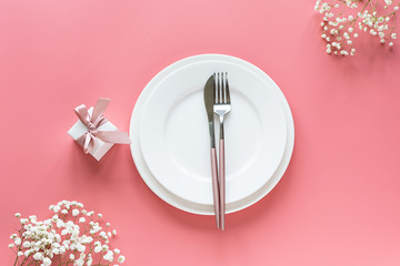 Beautiful festive composition with gift box and cutlery set on trendy pink background. Valentines...