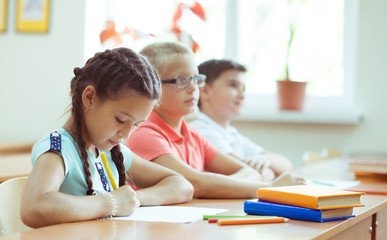 Obraz premium Cute schoolchildren study and answer questions in classroom during a lesson at primary school