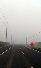 Foggy country road with caution sign