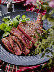 Steak on the bone. Rib eye. Tomahawk steak on the black plate with rosemary. Roasting - Rare. Entrecote