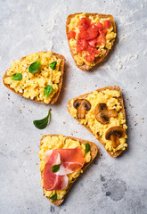 Scramble omelet sandwiches, bacon, mushrooms, tomatoes and fresh herbs on a light gray background.