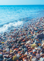 Bright wet pebbles on the coast in the foam of the surf