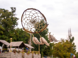 Dream catchers develop in the wind, easily and naturally, like birds in flight, against the backdrop of the beach and coastal buildings.