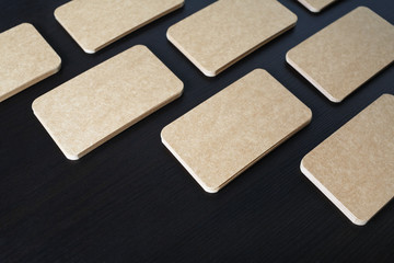 Photo of blank vintage business cards on black wood table background. Template for branding identity.