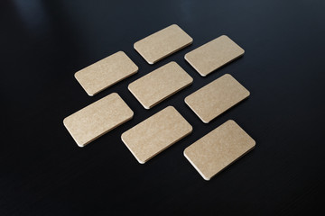 Blank kraft business cards lying in the shape of a heart on black wooden background.