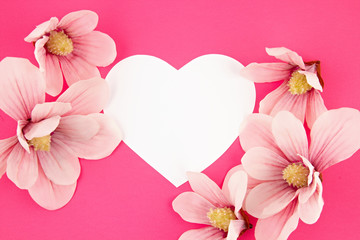 White paper heart and magnolia flowersover pink background. Love happiness, valentines day, mothers day concept