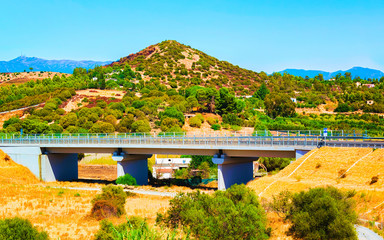 Empty road without cars under bridge at Villasimius in Sardinia Island in Italy summer. Transport...