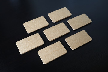 Photo of blank kraft business cards on black wooden background. Template for ID.
