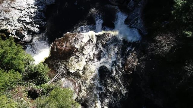 Cascading Blackwater Falls in rural forest, tilt down aerial