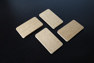 Stacks of blank kraft business cards on black wooden background. Template for branding ID.