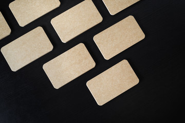 Mockup of kraft business cards on black wood table background. Flat lay.