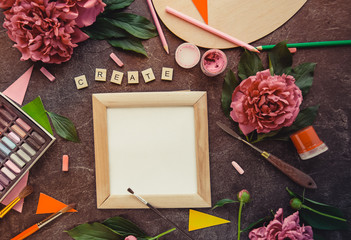 Artist Workspace with Create word typing on wooden blocks, photo frame, blank canvas, pink peony...