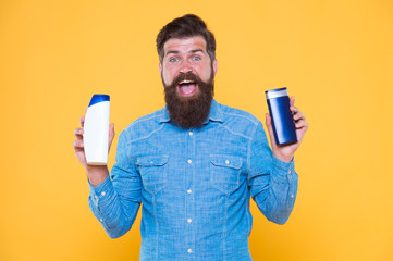 Grooming at every opportunity. Bearded man hold shampoo bottles yellow background. Cosmetics and toiletries. Hygiene and personal grooming. Male body grooming and skincare. Grooming products for men