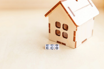 Miniature toy model house with inscription ECO letters word on wooden backdrop. Eco Village, abstract environmental background. Ecology zero waste social responsibility recycle bio home concept