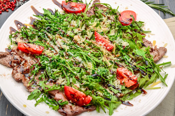 grilled meat sliced in thin slices with arugula
