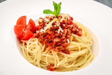spaghetti dinner with meat sauce and basil close up