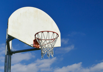 Basketball net in a wooden basketball hoop with blue sky and clouds