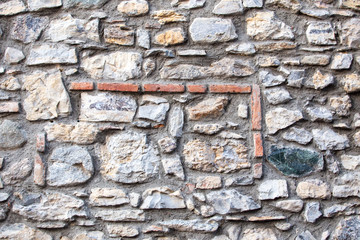 ancient irregular stone wall with red bricks