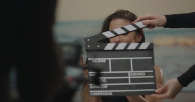 Clapper board hit on a film set in studio by a directress with an actress camera