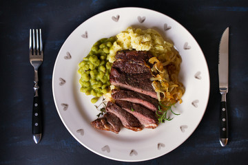 Grilled fillet beef steak with mashed potato, peas and fried onion. View from above, top view