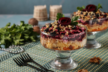 Traditional Russian salad with cheese, beets and carrots, decorated with beet roses, nuts and prunes, portioned serving, Horizontal orientation