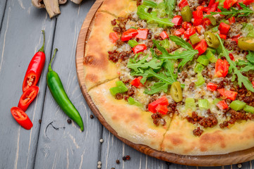 Traditional italian pizza with minced meat on wooden background