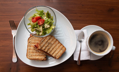 Desayuno, mesa con café, ensalada y emparedado o sandwich