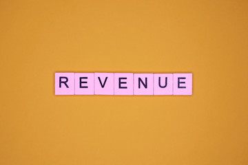 Revenue word wooden cubes on yellow background.