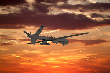 Fototapeta na wymiar military UAV airplane flies against backdrop of beautiful sunset sky is orange with clouds and condensation traces