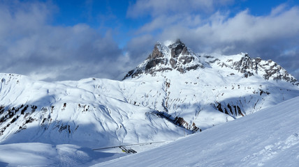 Panoramic winter landscape of high mountain peak in clouds and skiing slopes in Austrian Alps...