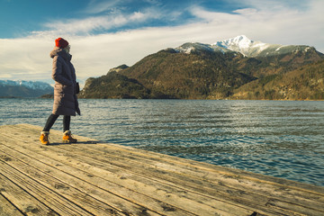 Fototapeta na wymiar life style travel girl portrait turn around posing on wooden pier enjoy by gorgeous beautiful picturesque scenic view of Austrian Alps mountains snowy peak winter time wallpaper landscape, copy space
