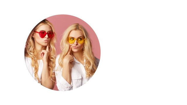 Portrait of two young happy, shocked women in the heart shape sunglasses looking throth the white hole in the wall. Big sale. Funny faces. Empty space for text