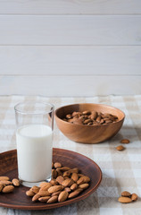 healthy food concept, almonds and glass of milk on a plate on the table