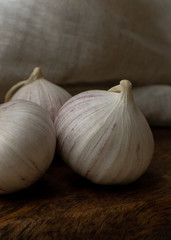 Three solo garlic on wooden table textile background close-up
