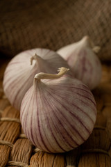 Three solo garlic on straw mat textile background close-up
