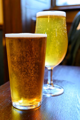 Misty glasses with two pints of cold Scotch ale, amber pale ale, lager draft beer in English pub