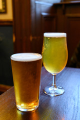 Misty glasses with two pints of cold Scotch ale, amber pale ale, lager draft beer in English pub