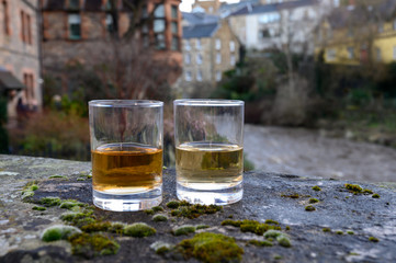 Scotch single malts or blended whisky spirits in glasses with old houses of Edinburgh on background, Scotland, UK