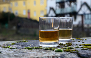 Scotch single malts or blended whisky spirits in glasses with old houses of Edinburgh on...