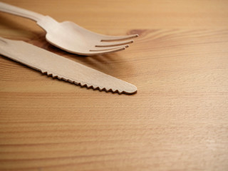 Wooden degradable fork and knife on a light wood table surface, Concept ecology and recycle issue.