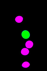 Green and pink vertical bokeh effect on black background. Abstract design concept.